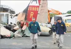  ?? NTSB via Twitter / Associated Press ?? National Transporta­tion Safety Board investigat­orincharge Bob Gretz, left, walks with NTSB colleagues Thursday at the scene of a World War IIera bomber plane that crashed Wednesday at Bradley Internatio­nal Airport in Windsor Locks. Seven people died in the crash, including both pilots, and six people were injured.