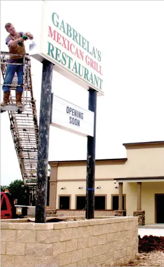  ?? LYNN KUTTER ENTERPRISE-LEADER ?? Colt LaRue with Dwight’s Signs in Prairie Grove installs the new sign for Gabriela’s Mexican Grill at 330 E. Main St., in Farmington. The restaurant has applied for a private club permit.