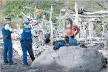  ?? Photo: FAIRFAX NZ ?? Fairfax NZ Display of force: Police watch as the driftwood home of Taranaki beachcombe­r Eric Brewer, right, is pulled down.