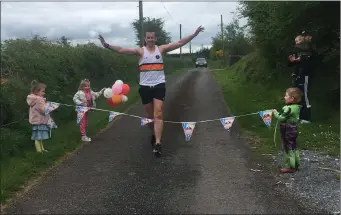  ??  ?? Shane Collins, Mourneabbe­y, crosses the line at the end of his first marathon for Cyctic Fibrosis Ireland on Sunday last, with his little band of little stewards making sure he completed the course.