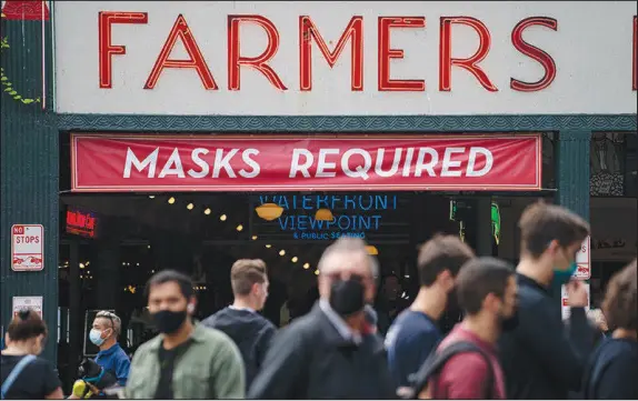  ?? RUTH FREMSON / THE NEW YORK TIMES ?? Pike Place Market in Seattle bustles with activity on Aug. 26. Signs outside the Seattle landmark tell customers to wear masks before entering as the contagious delta variant picks up momentum. Cities and large parts of the economy continued to bounce back this year, as if returning to some sense of normalcy. But when the pandemic’s path veered, so did our sense of where the finish line was.