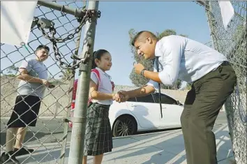  ?? Photograph­s by Al Seib Los Angeles Times ?? RUBEN ALONZO, 29, founder of Excelencia Charter Academy, greets Leah Ramirez, 5, on the campus of Sunrise Elementary School in Boyle Heights last month. At left is her father, Sergio.