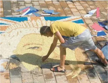  ?? SYLEJMAN KLLOKOQI/AP ?? Fine-grained image: Artist Alken Pozhega makes a giant portrait Saturday in the town of Gjakova, Kosovo, of Britain’s Queen Elizabeth II composed entirely of grains of corn, peas and beans. Elizabeth, Britain’s longest-reigning monarch and a rock of stability across much of a turbulent century, died Thursday at age 96 after 70 years on the throne.