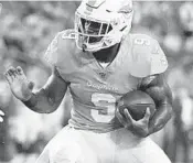  ?? JULIO AGUILAR/GETTY ?? Dolphins running back Mark Walton looks to get around Buccaneers’ Jordan Whitehead during a preseason game at Raymond James Stadium on Aug. 16.