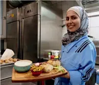  ?? — AP ?? Malakeh Jazmati carries food to be served to a customer in her restaurant in Berlin, Germany.