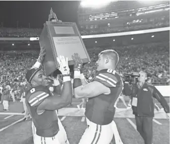  ?? JEFF HANISCH, USA TODAY SPORTS ?? Wisconsin’s Corey Clement, left, and Troy Fumagalli lift the Freedom Trophy, given to the Wisconsin- Nebraska winner.