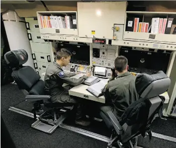  ?? C H A R L I E R I E D E L / T H E ASS O C I AT E D P R E SS ?? 1st Lt. Andy Parthum, left, and 2nd Lt. Oliver Parsons check systems in the undergroun­d control room at an ICBM launch control facility near Minot Air Force Base in North Dakota.