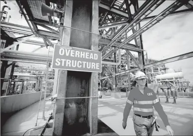  ?? BLOOMBERG ?? A worker walks through a project site operated by QGC, a unit of Royal Dutch Shell, in Gladstone, Australia.