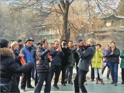  ?? PHOTOS PROVIDED TO CHINA DAILY ?? Musical ambassador Kyle Dillingham gives an impromptu performanc­e in front of the Oklahoma-Gansu friendship tree at the Five Springs Mountain Park, in the provincial capital, Lanzhou. The tree was planted as a gift from Oklahoma governor George Nigh on his 1985 trip to Gansu province.