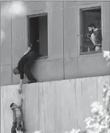  ?? Associated Press ?? A man hands a child to a security guard from Iran’s parliament building after an assault of several attackers, in Tehran, Iran, Wednesday.