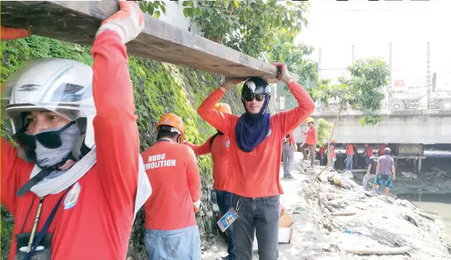  ?? PHOTO BY ALLAN CUIZON ?? TOUGH, BUT SOMEONE HAS TO DO IT: A crew from the Mandaue City Government tears down informal settlers’ houses on the edge of Mahiga Creek, before the next flood endangers them.