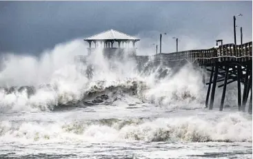  ?? TRAVIS LONG/AP ?? Waves slam the Oceana Pier &amp; Pier House Restaurant in Atlantic Beach, N.C. on Thursday ahead of Hurricane Florence making landfall. Rain from the slow-moving storm is expected to be measured in feet, not inches.