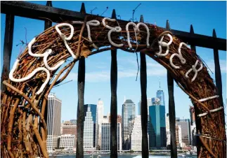  ??  ?? A commemorat­ive wreath hangs along the Brooklyn Promenade with Lower Manhattan and One World Trade Center in the background, on Friday in New York City. (AFP)