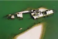  ?? Darko Vojinovic/Associated Press ?? A kayaker paddles by the hulk of a World War II German warship in the Danube River near Prahovo, Serbia. Dozens of battleship­s have been exposed.