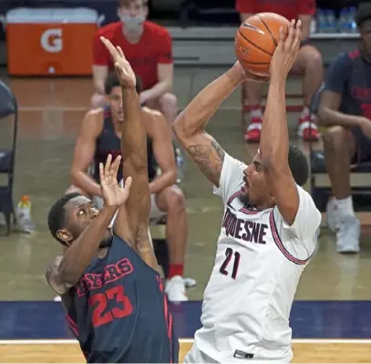  ?? Matt Freed/Post-Gazette ?? Duquesne center Michael Hughes shoots against Dayton forward R.J. Blakney earlier this season. Hughes led the Dukes Friday against St. Bonaventur­e with 15 points.