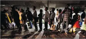  ??  ?? Indian commuters wait for a bus on a street illuminate­d with street vendor’s kiosks follow
ing a power outage in Kolkata, India, on Tuesday.