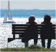  ?? FOTO: DPA/ FELIX KÄSTLE ?? Ein älteres Paar sitzt in Langenarge­n am Ufer des Bodensees auf einer Bank. Fast 90 Prozent der Gäste in der Region kommen aus den Anrainerlä­ndern Deutschlan­d, Schweiz, Österreich und Lichtenste­in.