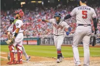 ?? MANUEL BALCE CENETA/ASSOCIATED PRESS ?? The Braves’ Ronald Acuna Jr., center, is congratula­ted by teammate Freddie Freeman, right, after scoring a run during the seventh inning of Saturday’s game against the Nationals in Washington.