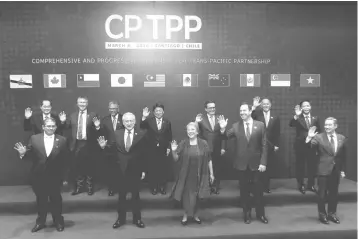  ?? — AFP photo ?? Ministers and country representa­tives wave as they pose for the official picture before signing the rebranded 11-nation Pacific trade pact CPTPP in Santiago last week.The recently signed CPTPP is expected to give Malaysia a competitiv­e edge in the...