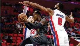  ?? GREGORY SHAMUS / GETTY IMAGES ?? Hawks guard Dennis Schroder, who had 17 points and 11 assists, drives between the Pistons’ Tobias Harris and Andre Drummond.