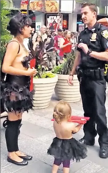  ??  ?? COVER UP! A police officer approaches a painted lady in Times Square on Monday, telling her to put a shirt on her little panhandlin­g partner — an approximat­ely 2-year-old girl.