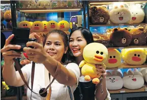  ?? — PHOTOS: SAKCHAI LALIT/THE ASSOCIATED PRESS ?? Customers take a selfie at a Bangkok store called Line Village, owned by the text-messaging service.