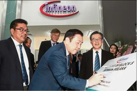  ??  ?? Latest investment: Ong signing on a plaque at the opening ceremony of Infineon’s new building.