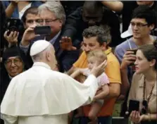  ?? ASSOCIATED PRESS ?? Pope Francis caresses a child as he arrives in the Paul VI hall at the Vatican for his weekly general audience, Wednesday.