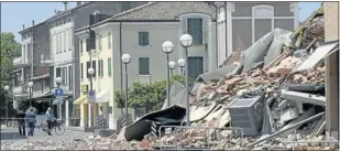  ?? Picture: REUTERS ?? RUIN: Residents walk past a building destroyed by an earthquake, in Cavezzo near Modena, yesterday.