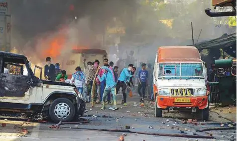  ?? PTI ?? ■ Protesters hurl bricks as smoke billows out of burning cars during India shutdown strike against the alleged dilution of Scheduled Castes/Scheduled Tribes act in Muzzaffarn­agar, Uttar Pradesh, on Monday.