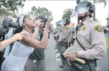  ?? Photograph­s by Hayne Palmour IV San Diego Union-Tribune ?? RASHIDA HAMEED yells at a San Diego County sheriff ’s deputy outside City Hall in National City on Tuesday as activists protest the death of Earl McNeil. Police said paramedics were checking on him when he died.