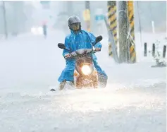  ??  ?? A motorcycli­st attempts to ride through floodwater­s, as Typhoon Nesat hits Pingtung county in southern Taiwan. — AFP photo