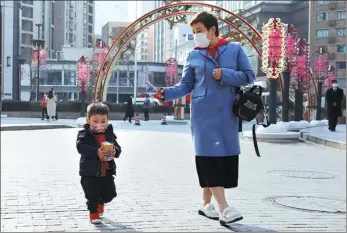  ?? YING LIQIN / CHINA NEWS SERVICE ?? A woman takes pictures of her child with a smartphone while they go shopping in Nanjing Street, Shanghai, on Feb 22.