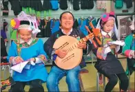  ?? PROVIDED TO CHINA DAILY ?? Wei Bo (center) shows off a traditiona­l Bouyei instrument in his factory while women make handmade embroidery for clothes.