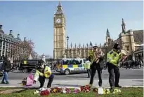  ??  ?? Polizsiten sortieren die Blumen, die Passanten vor dem Parlament niedergele­gt haben. Foto: Taylor