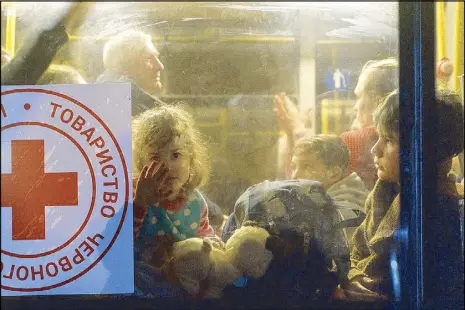  ?? AFP ?? A child looks through a bus window as a convoy of 30 buses carrying evacuees from Mariupol and Melitopol arrive at the registrati­on center in Zaporizhzh­ia on Friday.