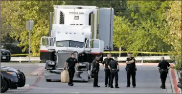  ?? The Associated Press ?? INVESTIGAT­ION: San Antonio police officers investigat­e the scene Sunday where nine people were found dead in a tractor-trailer loaded with at least 20 others outside a Walmart store in stifling summer heat in what police are calling a horrific human...