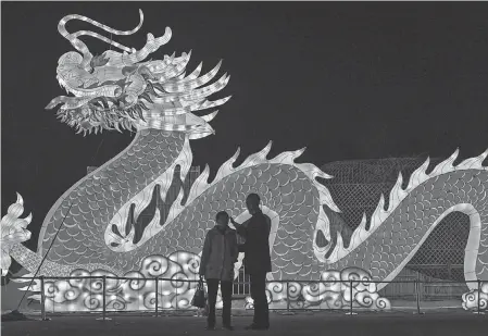  ?? HECTOR RETAMAL/ AFP VIA GETTY IMAGES ?? People talk in front of a giant dragon lantern in a park in Wuhan in China’s central Hubei province Thursday, ahead of the start of the Lunar New Year on Friday.