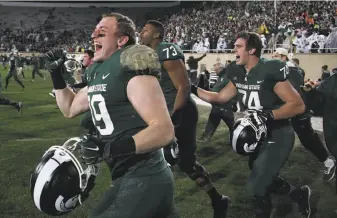  ?? Gregory Shamus / Getty Images ?? Michigan State players storm the field in East Lansing after the Spartans’ upset of Penn State.