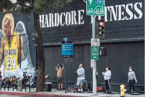  ?? Associated Press file photo ?? People wear masks as they work out outside the Hardcore Fitness gym in downtown Los Angeles in late January. The pandemic has changed how the fitness industry evaluates itself. The pandemic is reshaping America’s fitness industry and ushering in a new era of home workouts and virtual classes. High-end exercise equipment maker Peloton is breaking ground Monday on its first U.S. factory in Ohio.