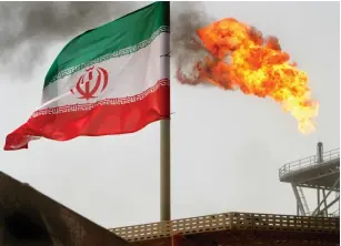  ?? (Raheb Homavandi/Reuters) ?? A GAS FLARE on an oil production platform in the Soroush oil fields is seen alongside an Iranian flag in the Persian Gulf.