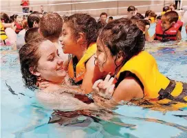  ?? [PHOTOS BY PAUL HELLSTERN, THE OKLAHOMAN] ?? Carl Albert High School student Briana Shaw plays with Yoselyn Lara and Elyssa Rivera during the Oklahoma Safe Kids’ Wee Water Wahoo safety program Friday at the Rose State College Aquatic Center in Midwest City.