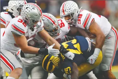  ?? The Associated Press ?? TAKEDOWN: Ohio State linebacker­s Tuf Borland (32), Davon Hamilton (53) and Malik Harrison (39) smother Michigan running back Hassan Haskins (25) in the second half of Saturday’s game in Ann Arbor, Mich.