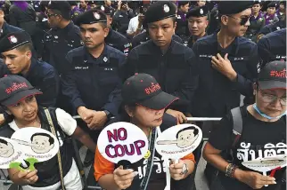  ?? AFP ?? DEMONSTRAT­ORS holding placards with a caricature depicting Thai Prime Minister Prayut Chan-O-Cha as Pinocchio stand next to police barricade outside Thammasat University during a protest to mark the fourth year of junta rule in Bangkok in this May 22...