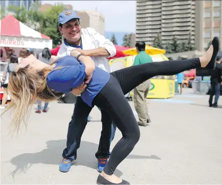  ?? PHOTOS: LEAH HENNEL ?? Hector Menjivar dips his daughter, Cindy Sosa, on Day 1 of Fiestaval in Calgary on Friday. The family has their food booth La Casa Latina set up at Olympic Plaza for the festival.