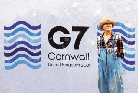  ?? AFP ?? A pedestrian poses for a photograph with a G7 logo outside the media centre at Falmouth, Cornwall on June 10 ahead of the three-day Group of Seven (G7) summit held from June 11-13.