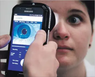  ?? MANUEL BALCE CENETA THE ASSOCIATED PRESS ?? Clinical Research Assistant Kevin Jackson measures Sarah Taylor’s eyes to assess her degree of pain. This experiment­al device aims to measure pain according to how pupils react to certain stimuli.