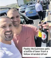  ??  ?? Paddy McGuinness gets a bottle of beer from a fellow stranded driver