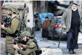  ?? PHOTO: REUTERS ?? Nasty business . . . A Palestinia­n man looks as an Israeli soldier aims a weapon during a protest in Hebron against the US Middle East peace plan.