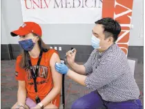  ?? K.M. Cannon Las Vegas Review-journal @Kmcannonph­oto ?? UNLV volleyball player Kate Brennan gets a COVID-19 vaccinatio­n from Andrew Choi at the university Monday, the first day eligibilit­y was extended to anyone 16 or older.